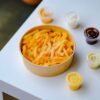 A tempting bowl of crispy french fries with various dips on a white table.