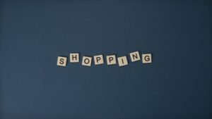 pexels photo 5912621 5912621 Alphabet tiles spell shopping on a blue background, ideal for retail themes.