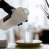 Close-up of liquid resin being poured into a plastic cup indoors.